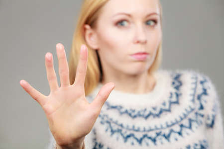 Denial, rejection gestures concept. Blonde woman making stop gesture with open handの写真素材