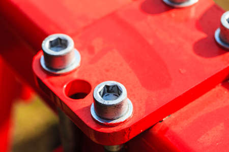 Construction machines concept. Detailed closeup of screw and bolts on red indrustrial machineryの写真素材