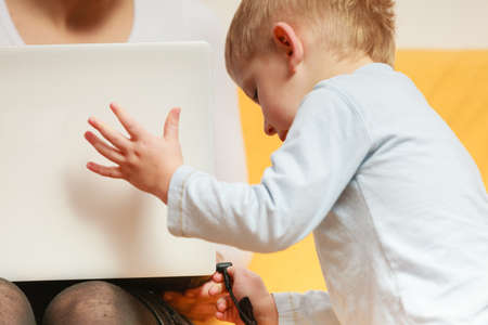 Working at home problems concept. Mother working and using laptop her little boy disturbingの写真素材