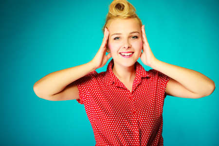 Shocking, amazed, astonished gestures concept. Shocked lovely pin up young girl holding head with hands. Studio shot on blue backgroundの写真素材