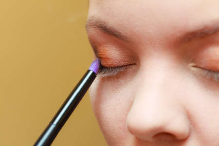 Visage concept. Close up woman getting make up on eyelids. Applying eyeshadow with brush, closed eyes.の写真素材