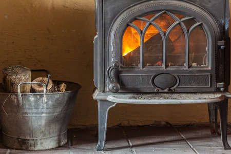 Winter at home. Fireplace with orange fire flame and firewood beside. Heating.の写真素材
