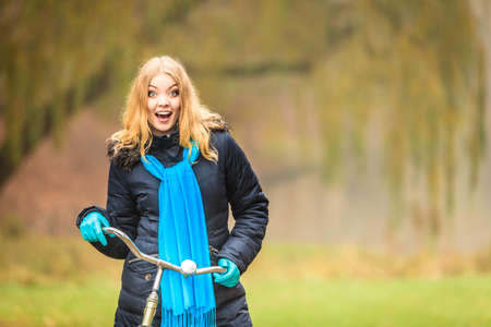 Happy active woman with bike bicycle in fall autumn park. Glad young girl in jacket and scarf relaxing. Healthy lifestyle and recreation leisure activity.の写真素材
