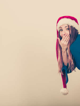 People modeling concept. Shocked lady behind the corner. Woman has blue top and santa claus cap with pompon.の写真素材