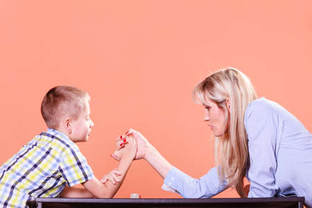 Spending time with family fun and family bonds. Mother and son arm wrestle and have fun indoors.