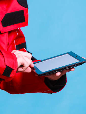 Young man using tablet. Male in windproof waterproof clothing. Internet connection adventure danger outdoors concept.の写真素材