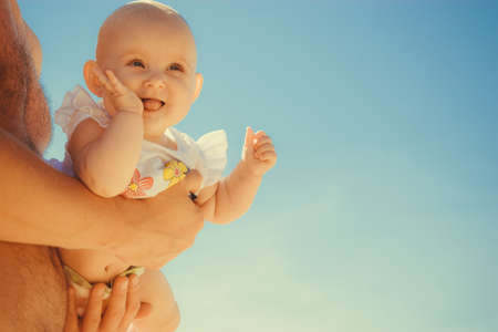 Closeup of happy sweet little baby in parent hands. Babyhood and parenting.