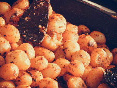 Healthy food concept. Backed young potatoes with spices and seasonings in black bowlの写真素材