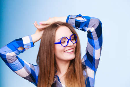 Studying, education and fun concept. Happy smiling nerdy woman in weird big glasses. Studio shot on...