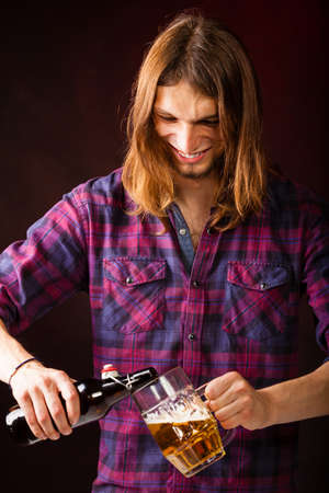 Alcohol drinking liquor relax party concept. Tapster fills stein from bottle. Young male bartender beer empties into glass.の写真素材