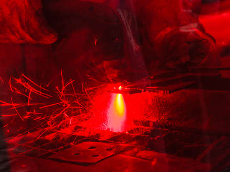 Technology, machines concept. Industrial laser cutting steel metal with bright red sparksの写真素材