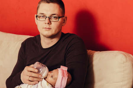 Parenting and love concept. Father holding and taking care of little newborn baby, feeding milk from bottle.の写真素材