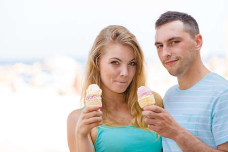 Relationship goals, summer love concept. Man and woman being on date, eating ice cream on beachの写真素材