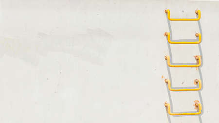 Simple objects pictures concept. Minimalist shot of yellow ladder on light grey conrecete wallの写真素材