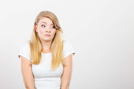 Face expression, emotions concept. Sad cute young blonde attractive woman in white t shirt.の写真素材