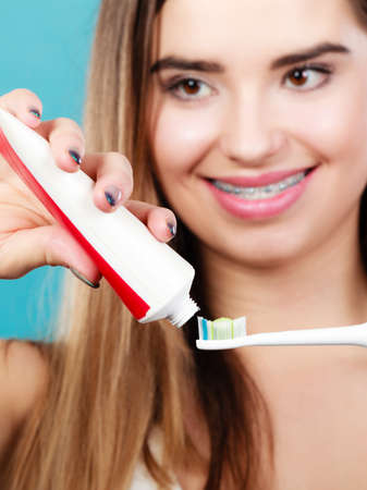 Dental oral hygiene concept. Woman with braces teeth holding toothbrush and applying toothpaste on...