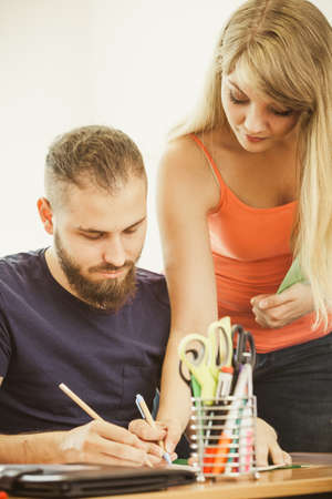 Teaching Concept. Female young teacher or tutor with male student in classroom with papers, laptop...
