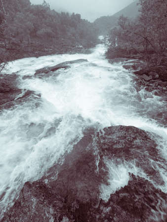 Travel, beauty in nature. Waterfall torrential river along the Aurlandsfjellet mountains in Norway Sogn og Fjordane, foggy hazy summer dayの写真素材