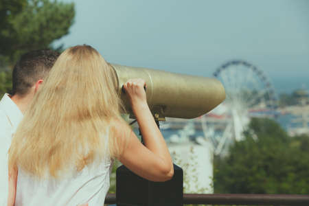 Love, romantic walks concept. Man and blonde woman looking through city telescope, sightseeing...