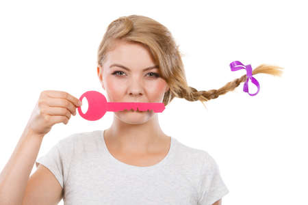 Language barrier concept. Teenage blonde girl with braid hair holding pink key on lips