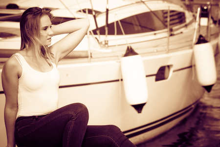 marina place beauty fashionable blondie woman sitting in boats harbor travelling conceptの写真素材