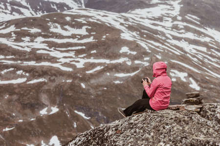 tourism vacation and travel female tourist taking photo with camera enjoying mountains landscape from dalsnibba viewpoint norway scandinaviaの写真素材