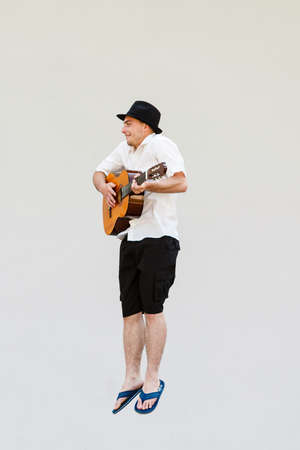 music passion hobby concept man in sun hat jumping and playing on guitarの写真素材
