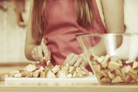 Woman young housewife in kitchen at home preparing fresh salad slicing apple fruits on cutting board. Healthy eating, cooking, vegetarian food, dieting and people conceptの写真素材