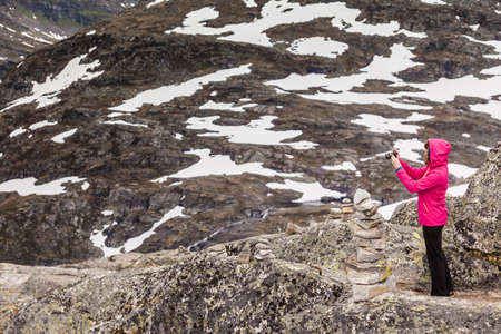 Tourism vacation and travel. Female tourist taking photo with camera, enjoying mountains landscape from Dalsnibba viewpoint, Norway Scandinavia.の写真素材