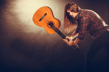 Rock music energy people feelings concept. Mad rock guitarist destroys his guitar.の写真素材
