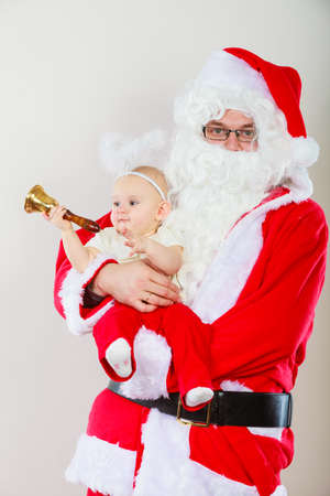 Christmas time people concept. Santa claus with little baby. Man has red outfit and child is hugging him. Shot taken at studio.の写真素材