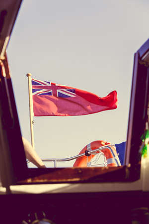 The uk red ensign the british maritime flag flown from yacht sail boat, blue sky and baltic sea. Summer and travel voyageの写真素材