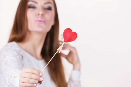 Valentine's day gift concept. Beautiful woman holding love sign, heart shaped wooden hand stick, studio shot on white backgroundの写真素材