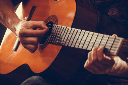 Closeup on musical instrument. Young person holding guitar. Music sound hobby passion concept.