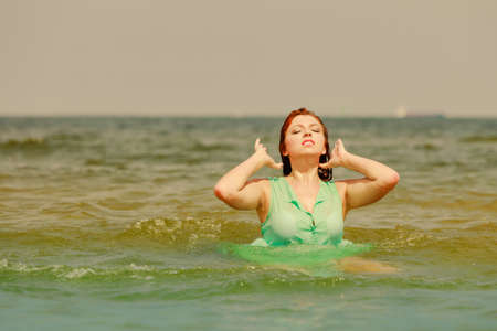 Summer fun, recreation outside concept. Redhead adult woman playing in water during summertime, having great time and smiling joyfullyの写真素材