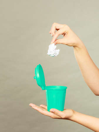 Cleaning, Woman putting paper into tiny trash can basket showing how to deal with rubbishの写真素材