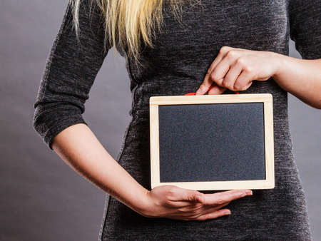 Tummy belly problems, pain, digestion, constipation concept. Woman holding blank black board on stomachの写真素材
