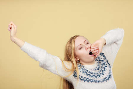 Tiredness, too much work at school concept. Sleepy yawning blonde teenage woman in jumper feeling exhaustedの写真素材