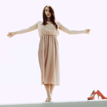 Fashionable clothing, fashion and trends concept. Woman in long dress standing and posing barefoot, high heels standing next to her.の写真素材