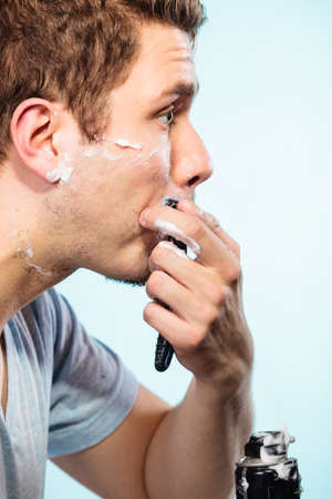 Man shaving using razor with cream foam. Guy removing face beard hair. Skin care and hygiene.の写真素材