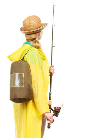 Fishery, spinning equipment, angling sport, activity concept. Woman wearing raincoat and backpack holding fishing rod, ready for adventure.の写真素材