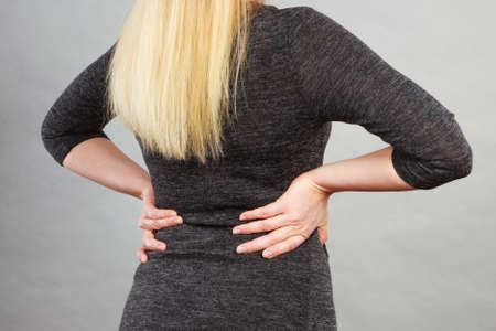 Woman wearing tight black dress showing her feminine body shape, back view.