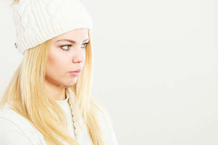 Winter fashion. Young blonde woman wearing fashionable wintertime clothes white woolen cap, studio...