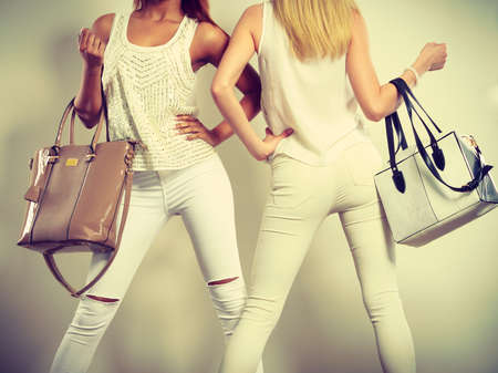 Fashion concept. Two slim women wearing white clothing with leather bags handbags.の写真素材