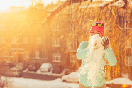 Girl having fun time with snow. Young woman playing in winter park. Health nature relax fashion fitness concept.の写真素材