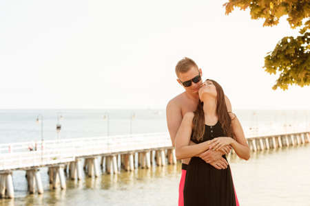 Spending romantic vacation together concept. Lovely couple, man and woman standing, hugging near beach during summertime.の写真素材