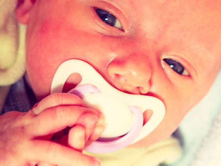 Infant care, beauty of childhood concept. Little newborn baby lying calmly in bed with teat in...