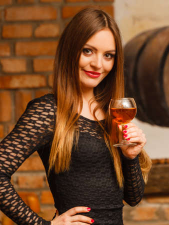 Elegant beauty lady long hair full make up wearing black dress tasting wine in rural cottage interior cellerの写真素材