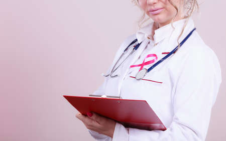 Doctor with diagnosis. Part body of female specialist holding red folder with disease files. Pink breast cancer awareness ribbon.の写真素材