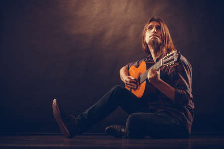 Music, hobby ceoncept. Focused man with guitar. Young boy is holding his instrument and thinking...